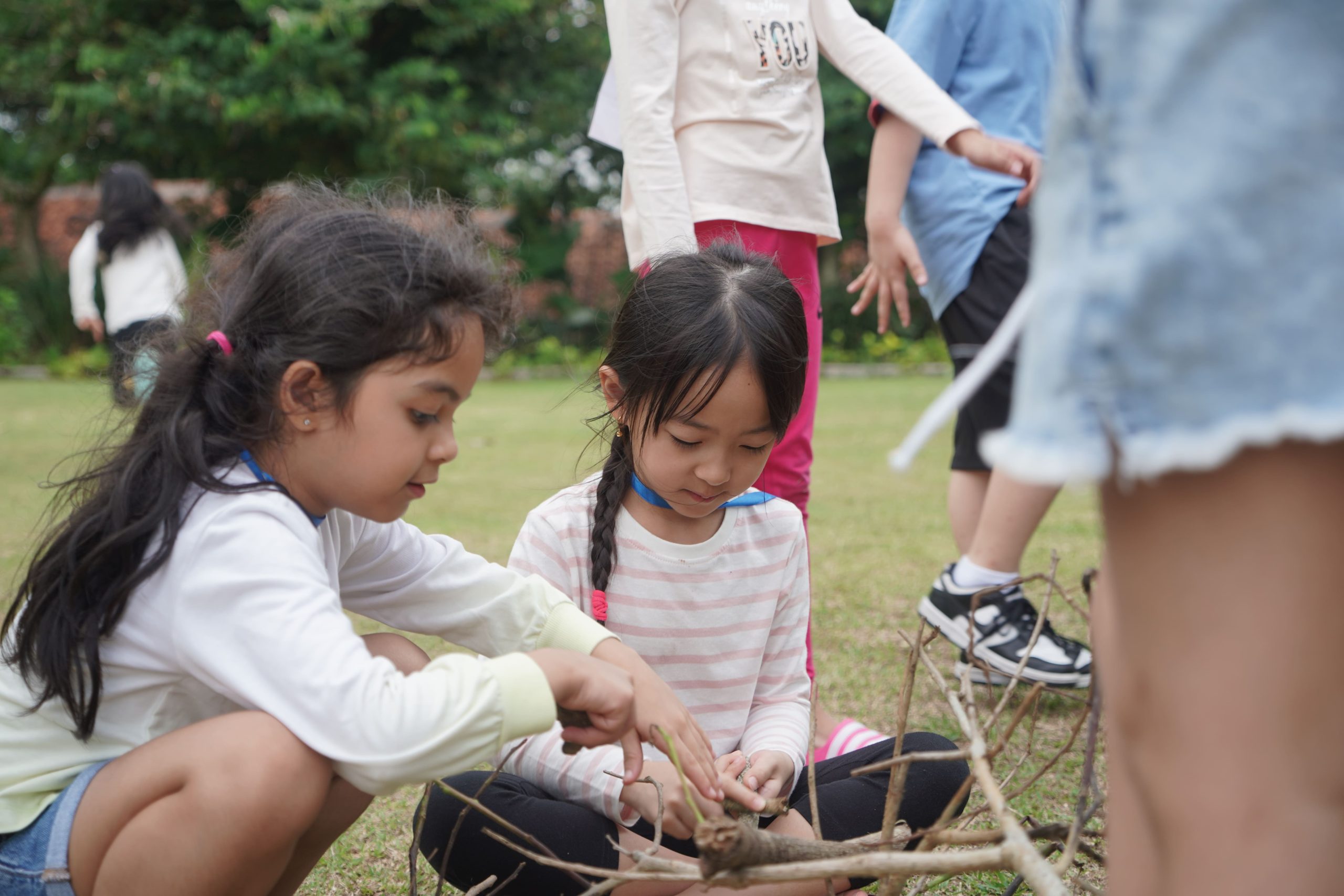Young students working together to build a shelter from sticks outdoors