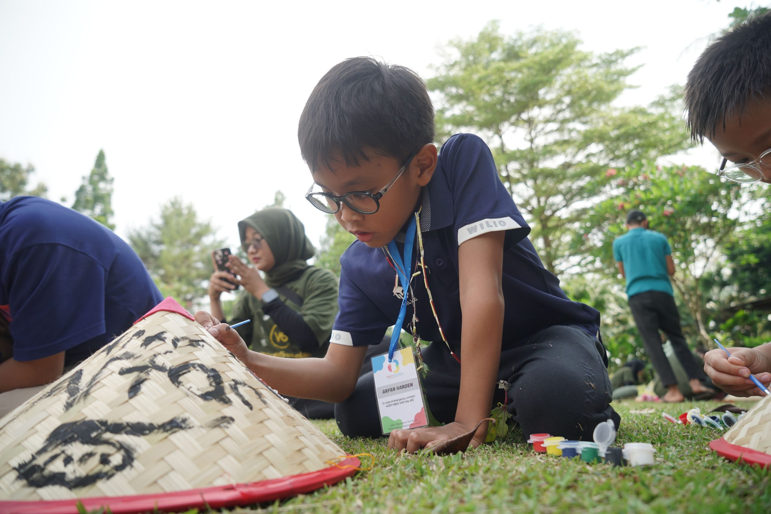 A student carefully painting a traditional woven hat during a hands-on craft activity