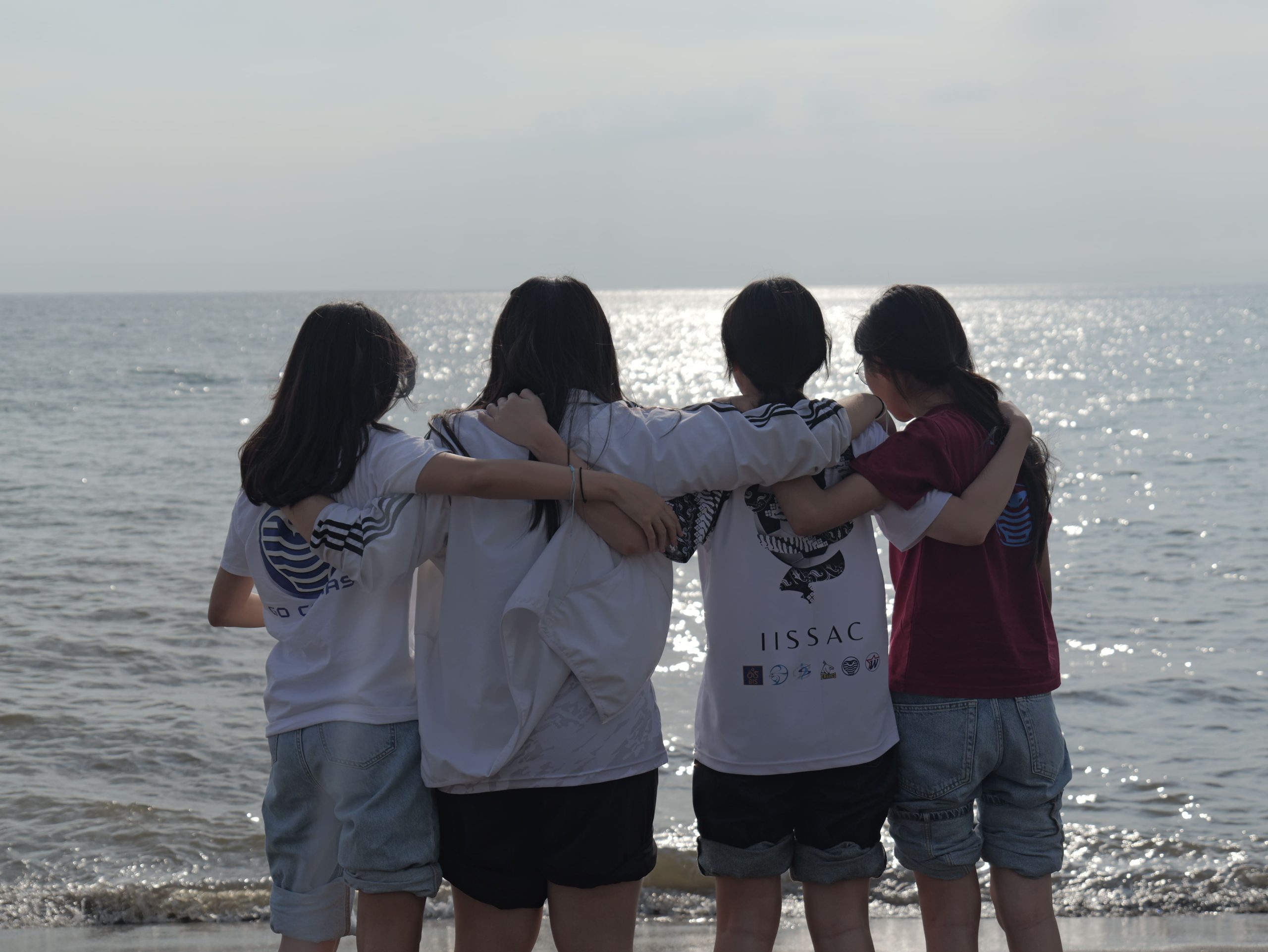 Students standing arm in arm, looking out at the ocean together
